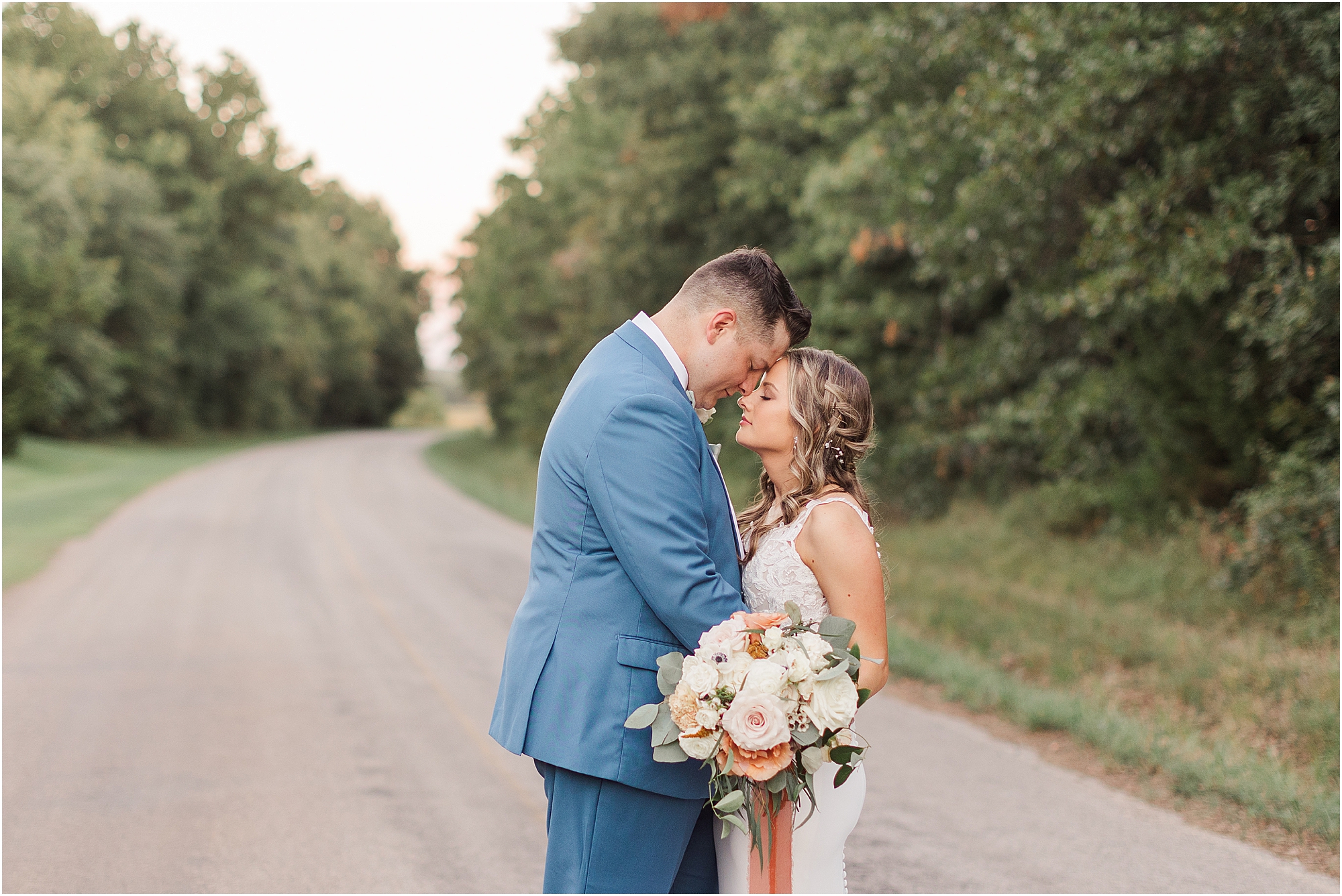 Caitlin and Riley sharing a moment on a country road in the woods of Oklahoma at their wedding venue Eleven Oaks Ranch.