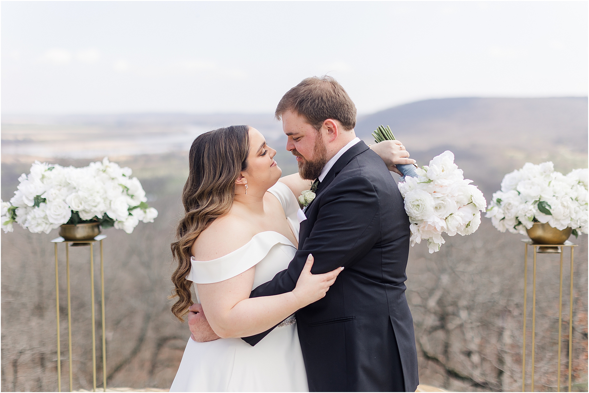 Brandi and Wade embracing at their Dream Point Ranch Wedding at the ledge of a valley view. 