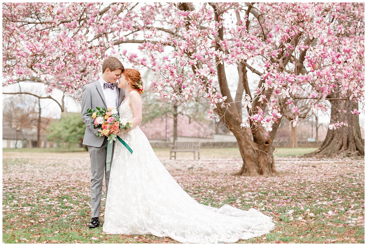 Bride and groom under a cherry blossom tree on a rainy spring wedding day.