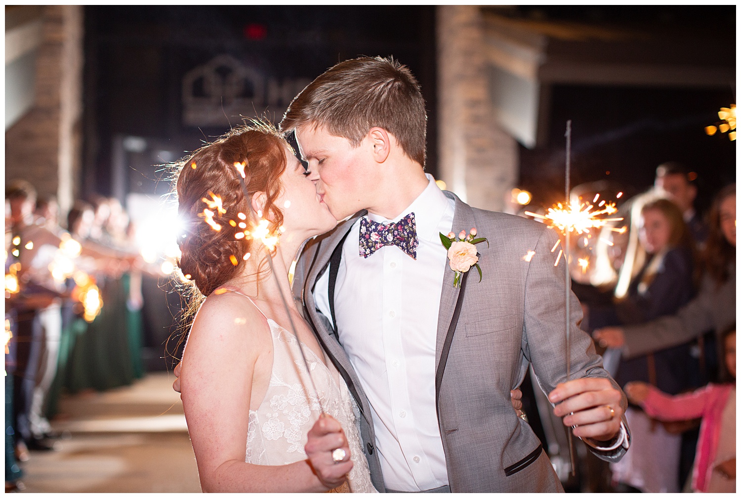 Bride and groom sharing a kiss with sparklers after their rainy wedding in the spring.