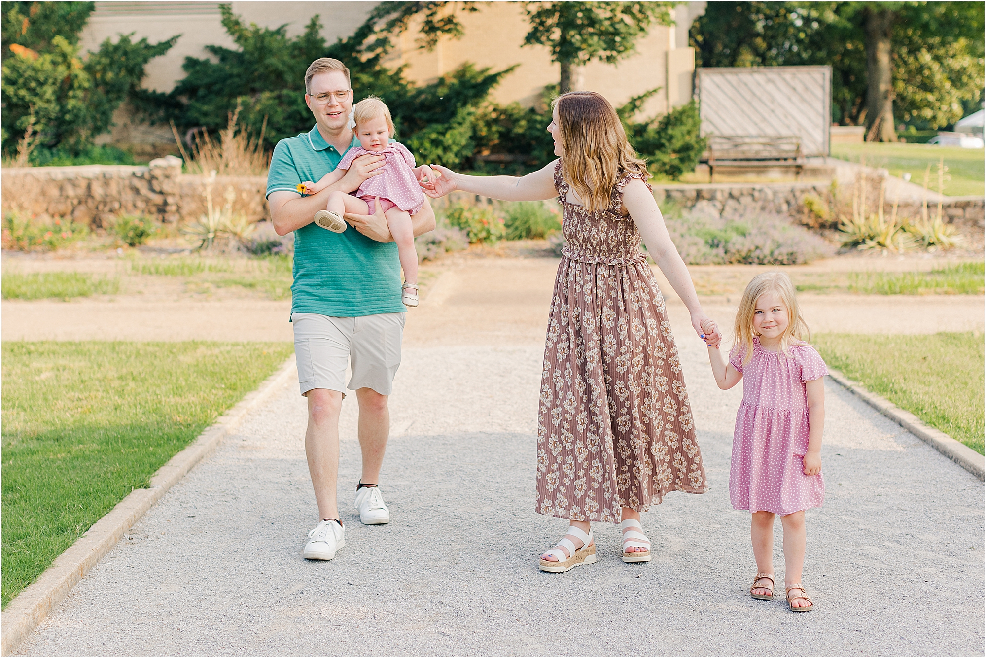 The family walking through the rose garden at woodward park at their summer family photo session.