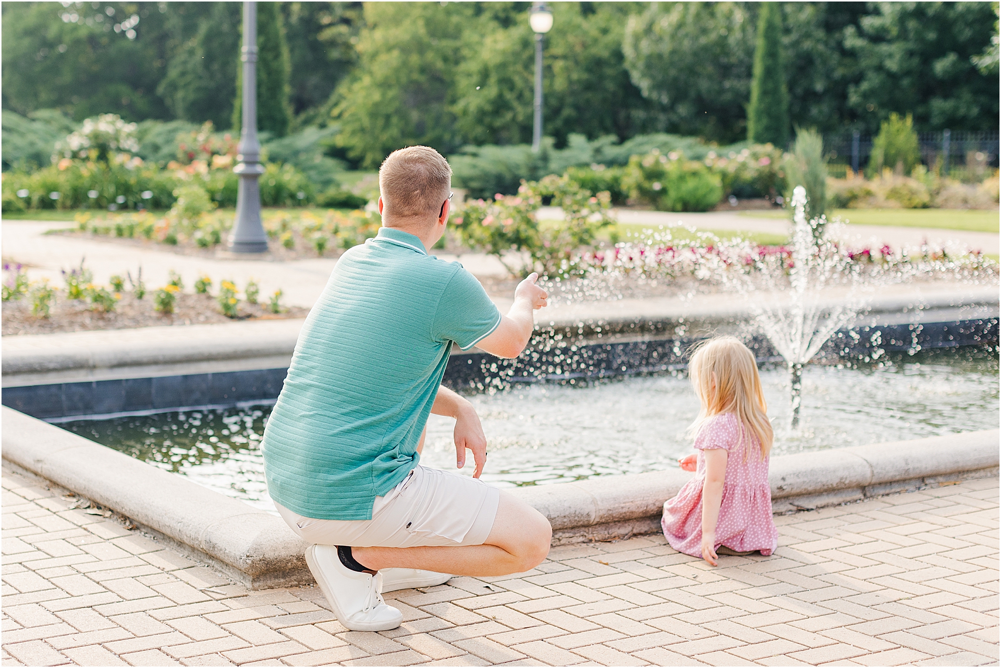 Daddy and daughter throwing pebbles in the fountain at a summer family photo session.