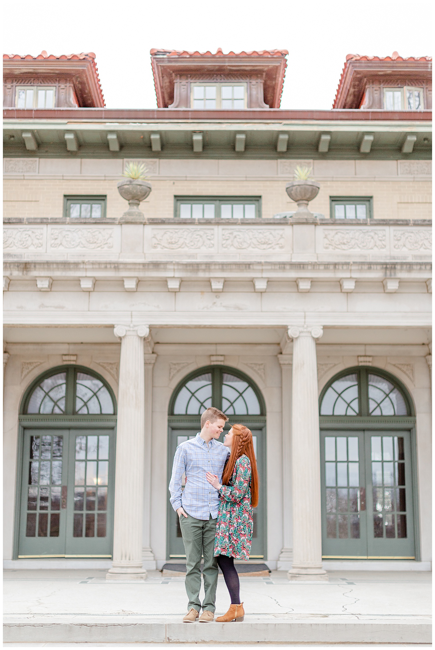 A couple on the porch of the mansion at woodward park during their engagement session in the Spring.