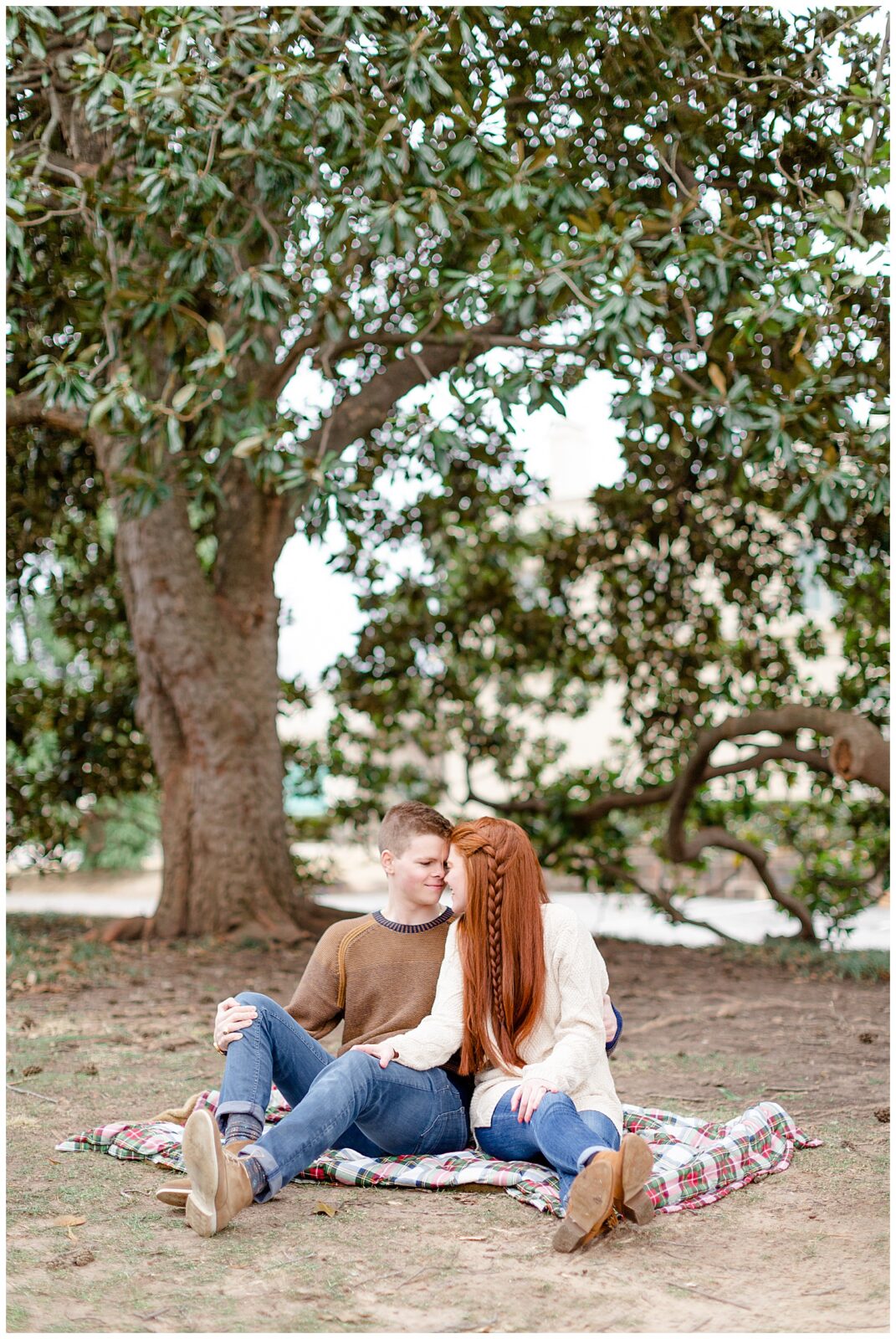 grant and ashley in front of the magnolia tree at woodward park during engagement photos. 