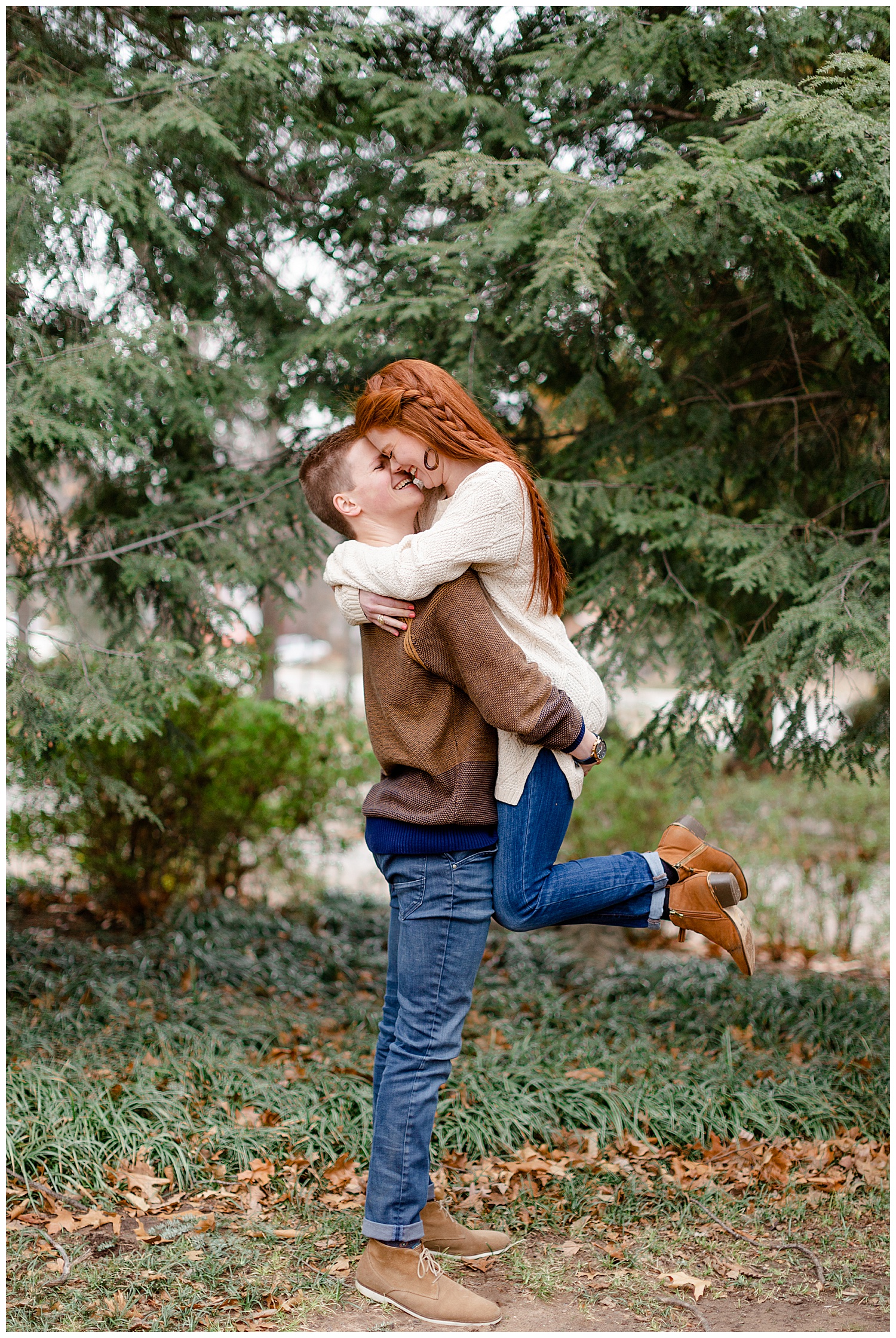 Grant picking Ashley up to kiss her during their Spring engagement session in the evergreen trees.