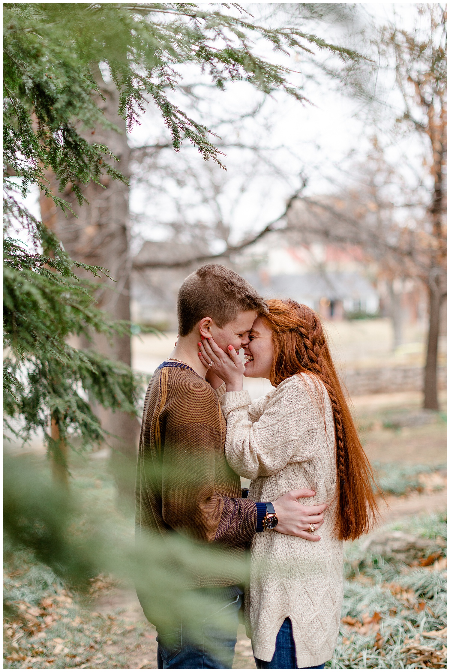 a couple kissing in the evergreen trees for their engagement photo session in the spring. 