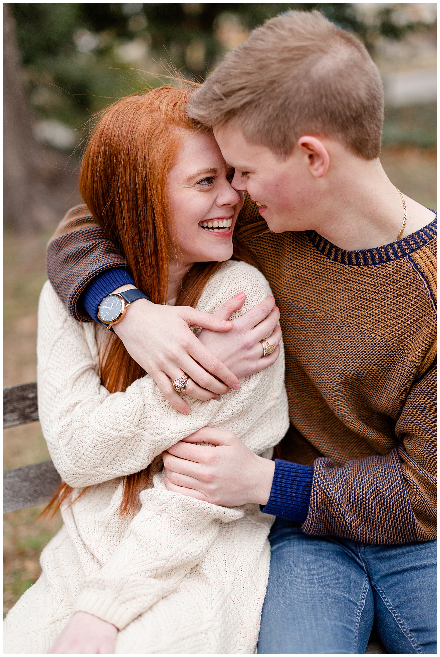 A couple hugging and wearing their class rings during their engagement photos at woodward park.