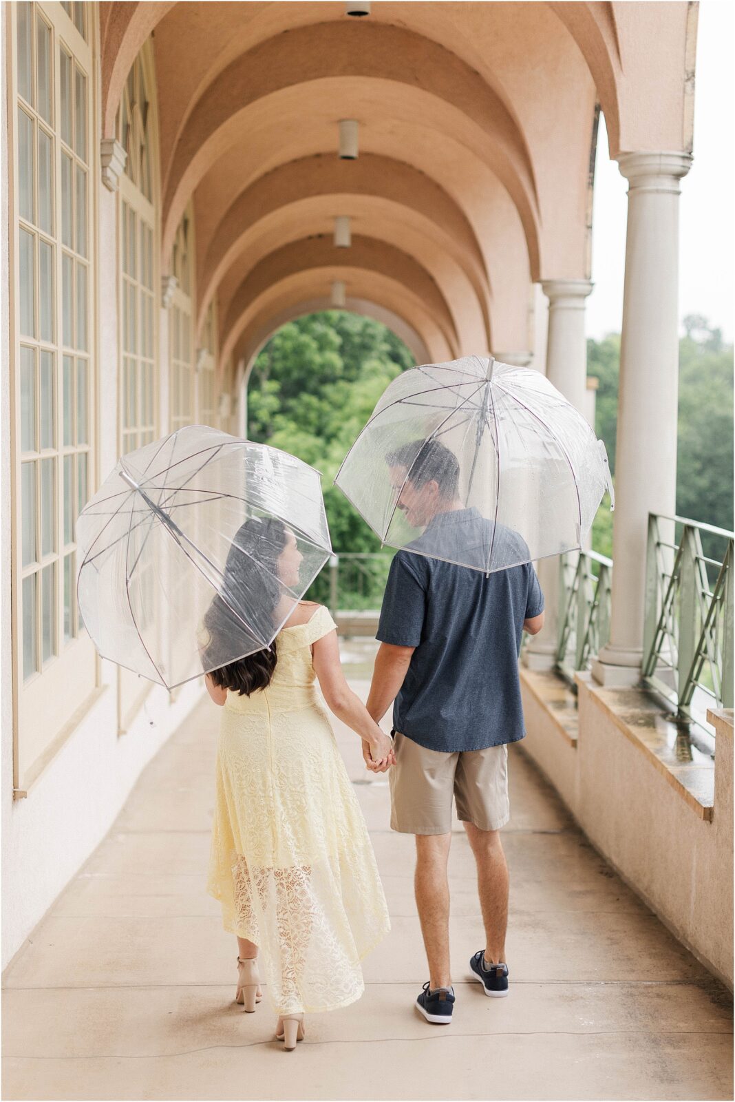 Bride and groom walking hand in hand at a rainy engagement session at the philbrook