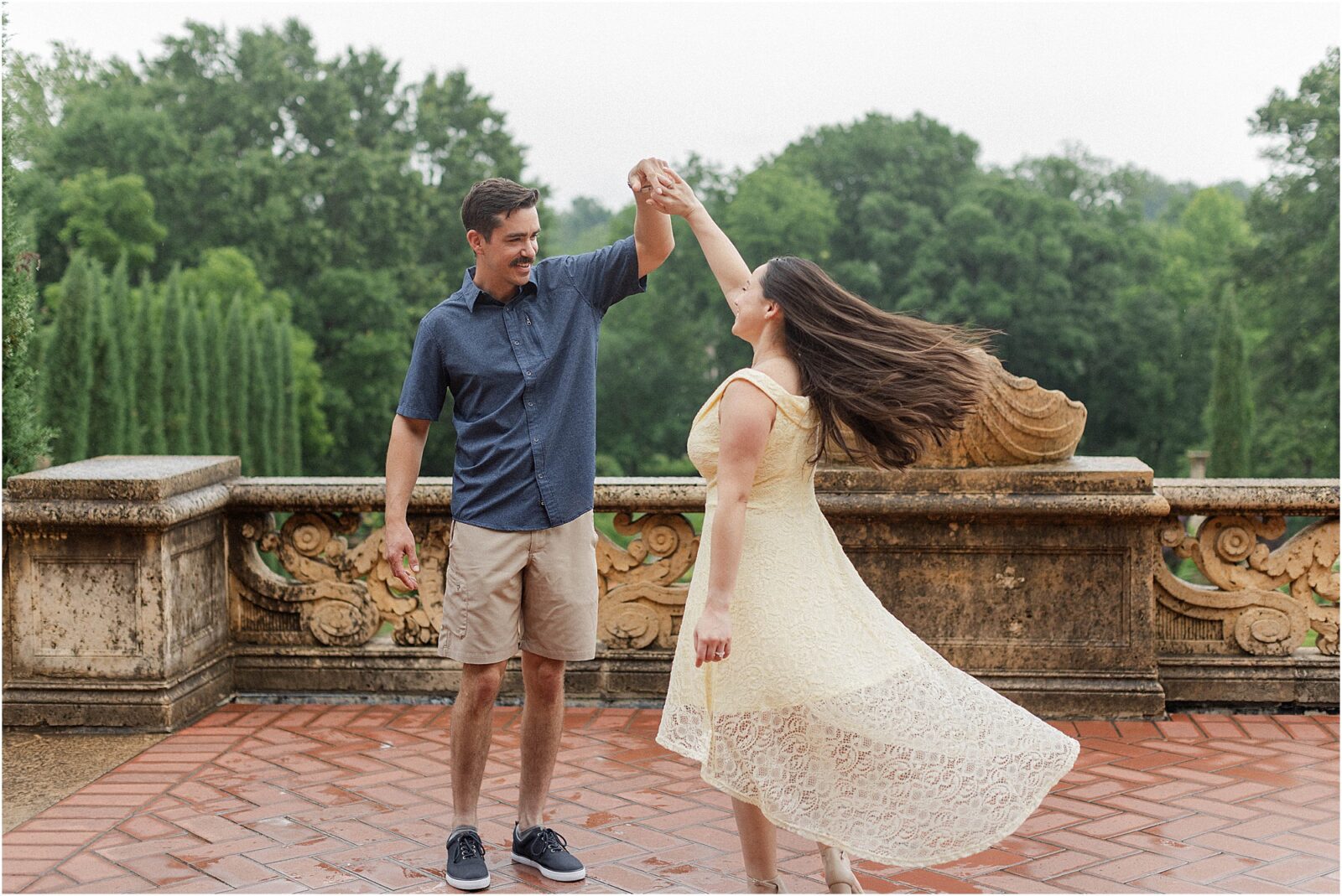 Bride and groom dancing on the balcony of the mansion during their rainy engagement session at the philbrook